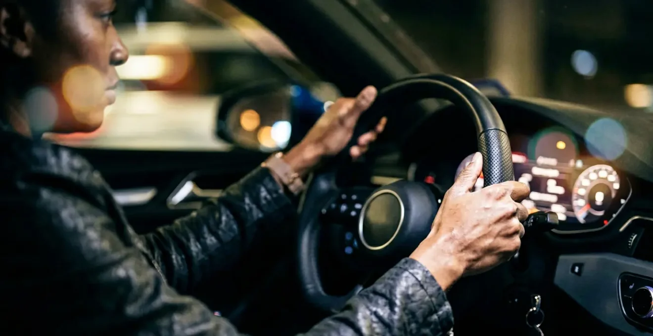 Close-up view of hands gripping a sports car steering wheel during a sudden lane change maneuver, showing tension and control