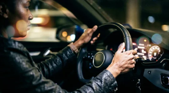 Close-up view of hands gripping a sports car steering wheel during a sudden lane change maneuver, showing tension and control