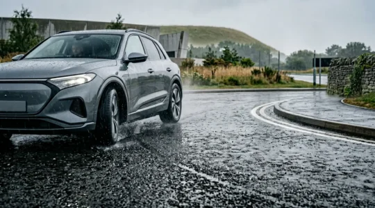 Close-up view of vehicle tire gripping wet asphalt surface under rainy conditions showing advanced safety technology in action