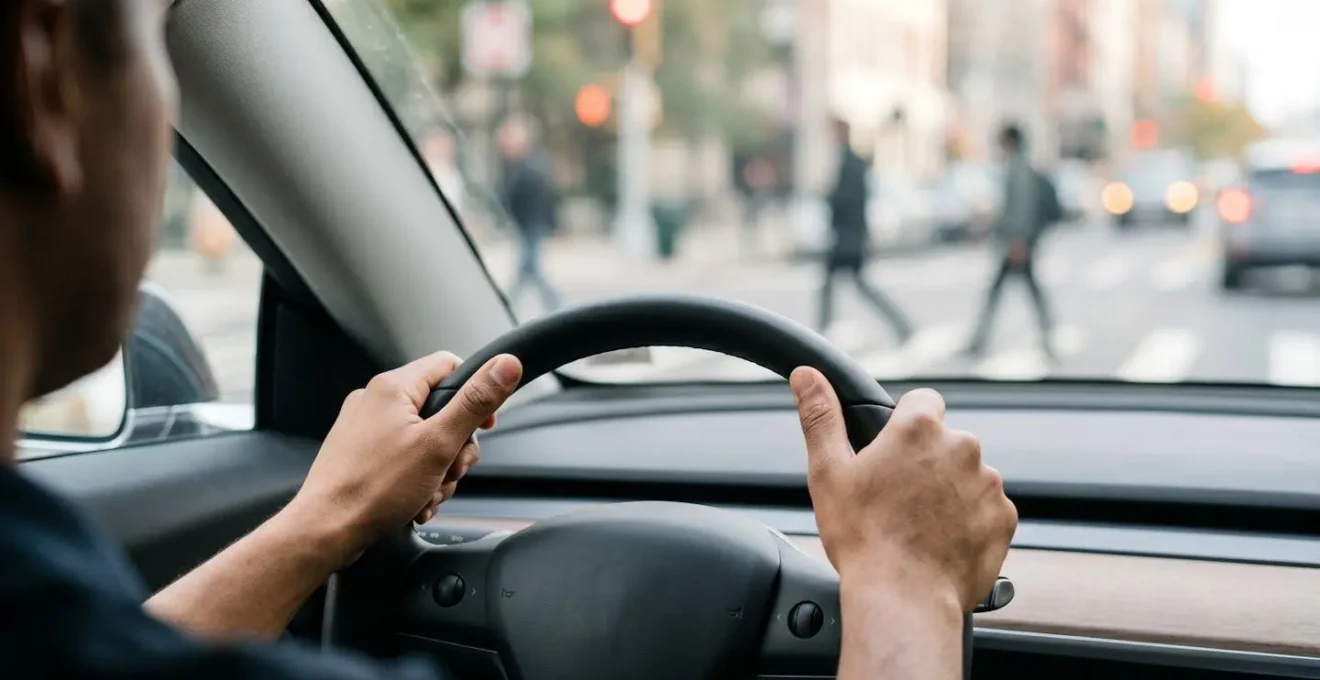 Human perspective view showing driver's hands on steering wheel with road ahead during active safety system intervention