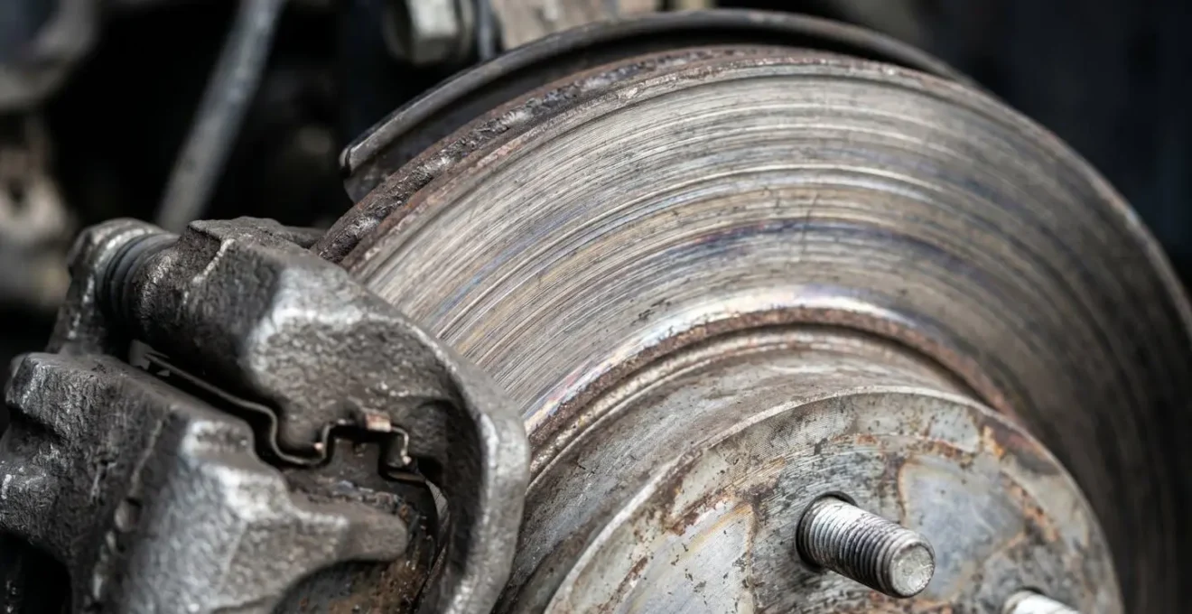 Close-up macro view of vehicle brake components showing wear patterns from aggressive driving habits affecting fuel economy