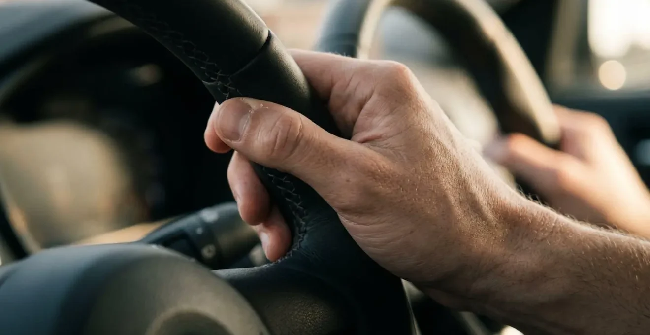 Close-up of driver's hands gripping steering wheel with tension, suggesting immediate takeover from automated system