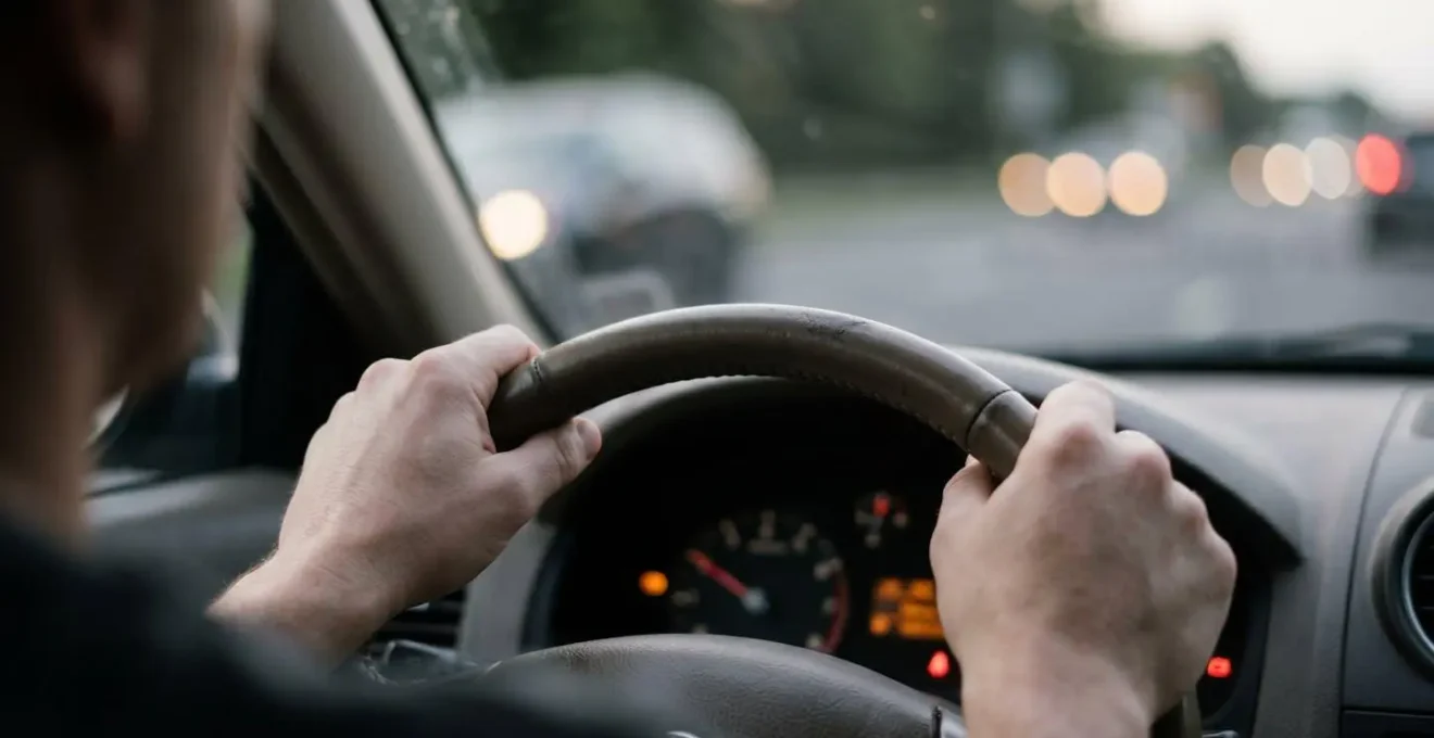 Driver hands on steering wheel with dashboard warning lights visible showing moment of decision