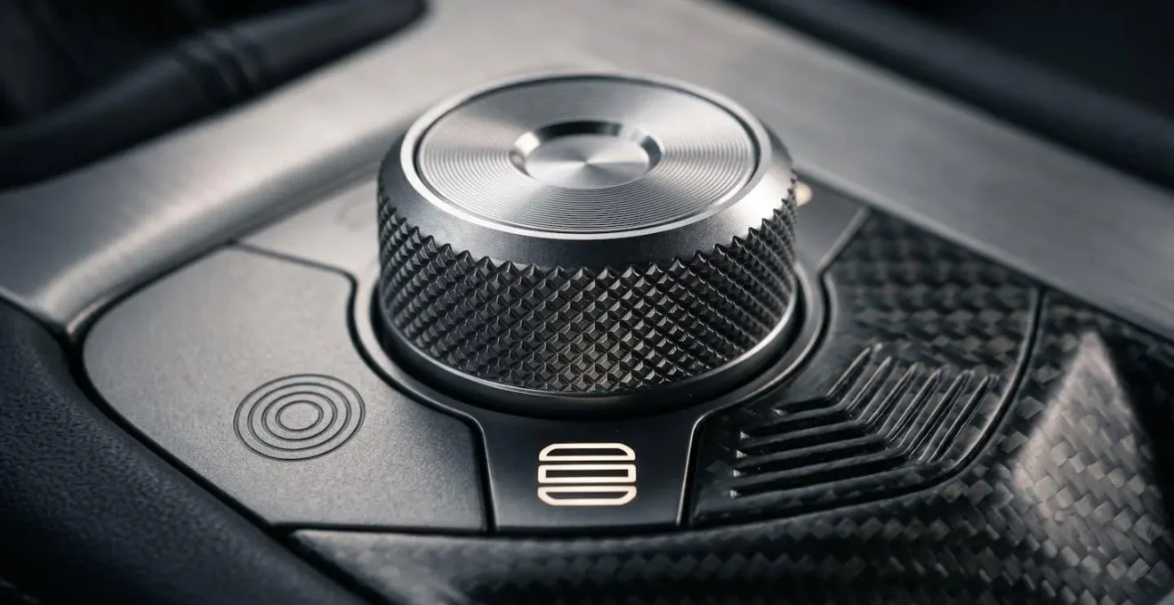 Macro detail of a modern performance car's drive mode selector dial showing Sport and Track settings with subtle metallic textures