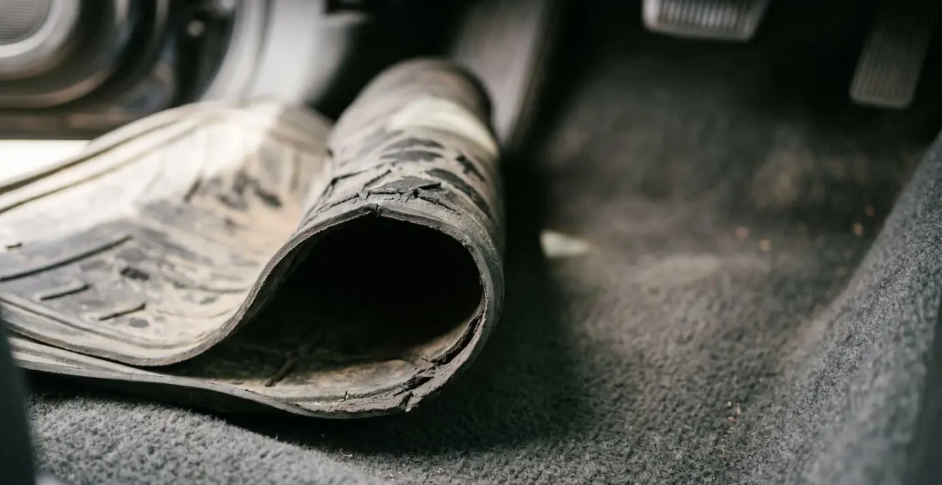 Close-up of degraded floor mat edge showing curling and abrasion damage from heel pivot wear